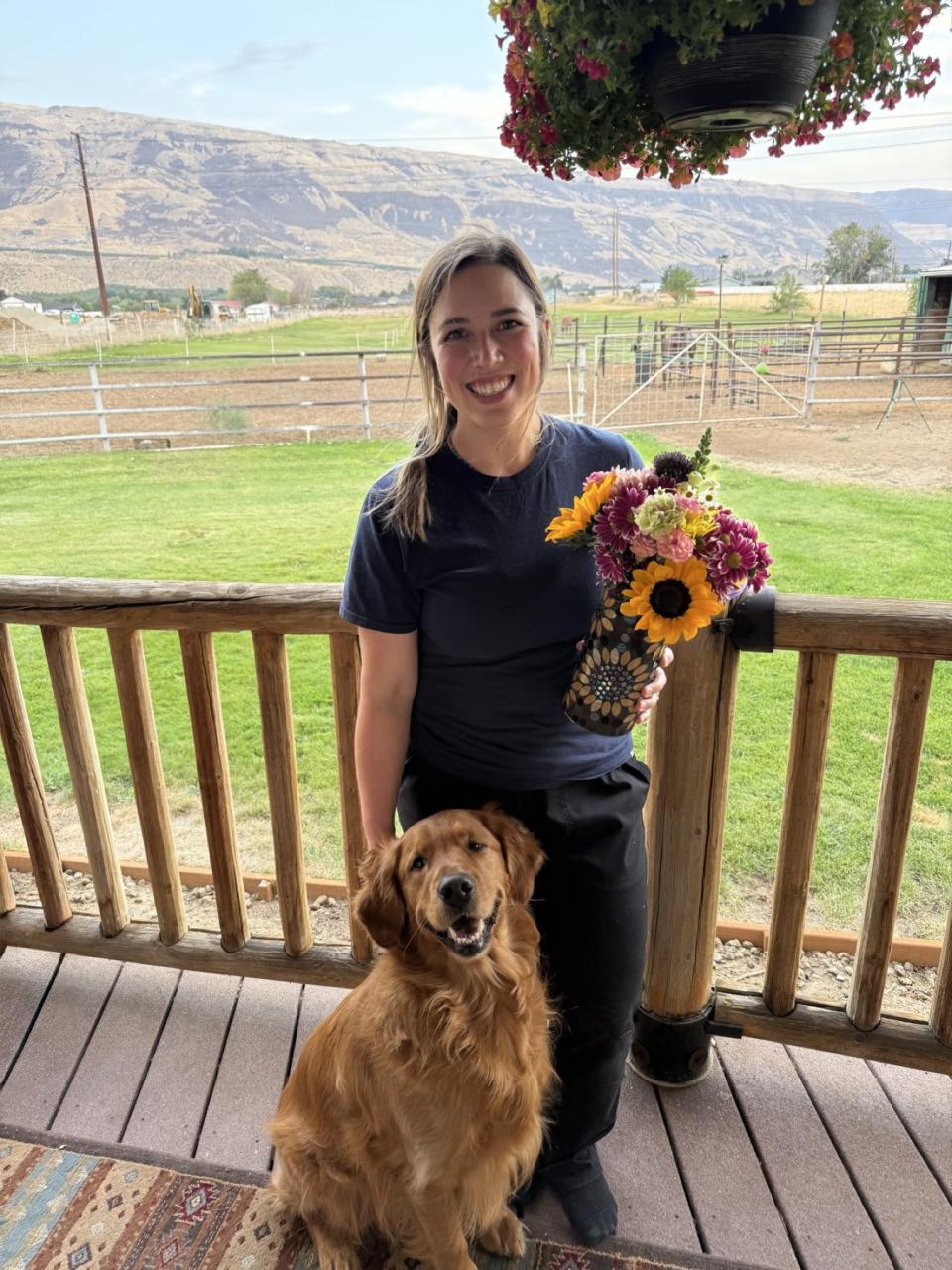 Sabrina Fitzgerald smiling with flowers beside one of her dogs after becoming a Licensed Veterinary Technician.